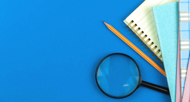 istock School flat lay composition with notebooks pencil and magnifying glass, student prepares for school days concept, blue background with copy space 1323580378