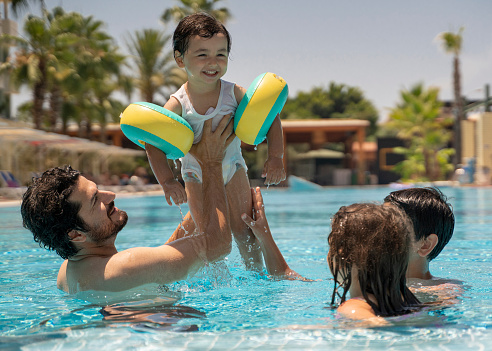 Father with kids having fun in swimming pool, holiday resort