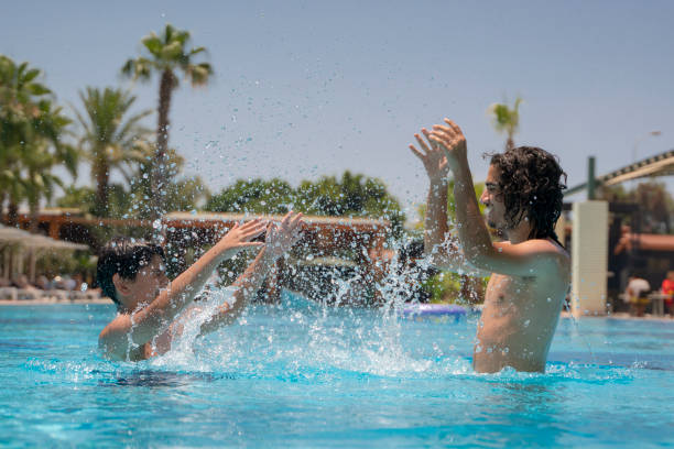 istock Boys having fun in swimming pool, holiday resort 1323581114
