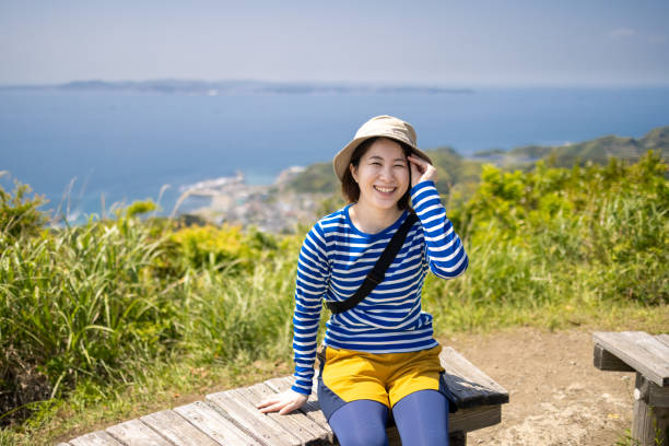 istock Young woman sitting on bench at mountain observation point 1323583477