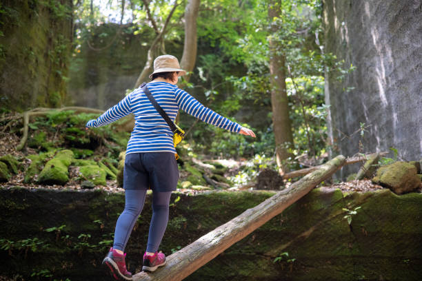istock Young woman walking on fallen tree trunk 1323584962