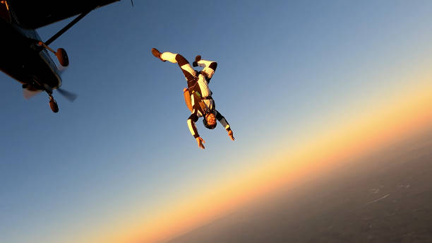 日没時に晴れた空に飛び乗るスカイダイバー。 - airplane stunt yellow flying ストックフォトと画像