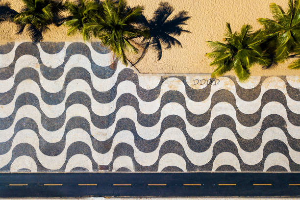 Top View of Copacabana Mosaic Sidewalk Rio de Janeiro, Brazil - April 9, 2021: Famous mosaic of Copacabana beach sidewalk and palm trees view from the top. copacabana rio de janeiro photos stock pictures, royalty-free photos & images