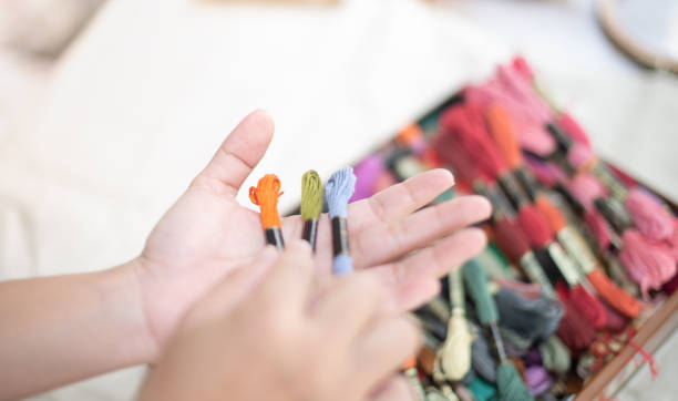 feche as mãos da mulher alfaiataria segurando muitos fios de cores diferentes na mesa e prepare-se para usar com algodão branco e madeira de moldura. - colors order wool thread - fotografias e filmes do acervo