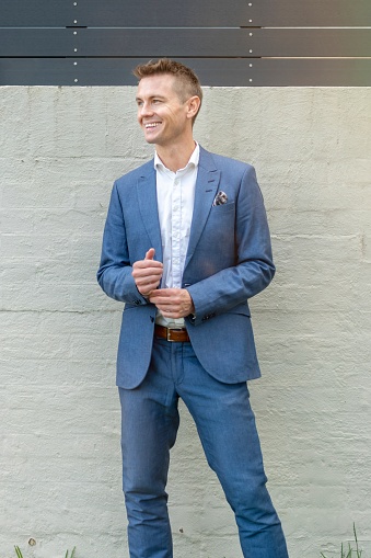 Portrait of a caucasian business man standing outside. Smiling off into the distance. Wearing a smart looking corporate suit.