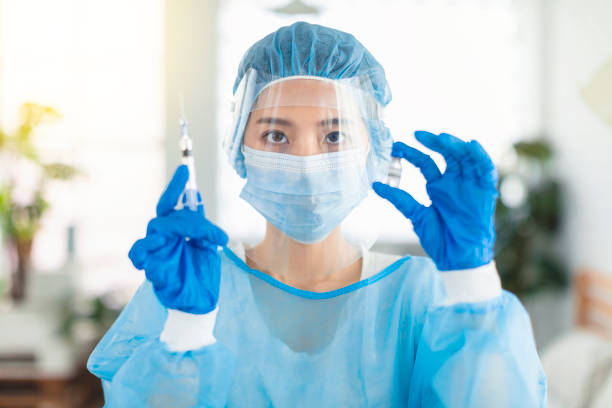 istock Doctors or nurses  wearing masks, eye shields, to prepare an injection with  syringe 1323589202