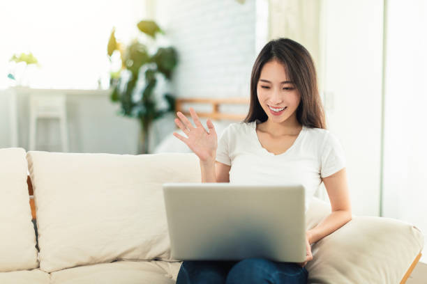 istock Young women working from home, sitting on the sofa using laptops for telecommuting, and video chatting with colleagues 1323589208