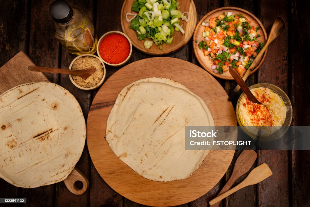 Naan flatbread High angle view of naan bread with ingredients in the kitchen at home over rustic wood table. Above Stock Photo