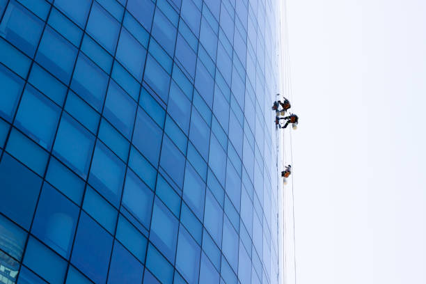 istock Window washers hanging outside blue glass modern building 1323597400