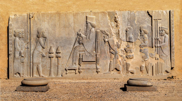 Relief of the Enthronement Relief of the Enthronement of Darius, Persepolis, Unesco World Heritage Site, Iran. Relief in the eastern portico of a Courtyard depicting King Darius Seated on a Throne with His Son Xerxes Standing Behind Him. Persepolis was the capital of the Achaemenid Empire. It is in northeast of the city of Shiraz in Fars Province, Iran. persian empire stock pictures, royalty-free photos & images