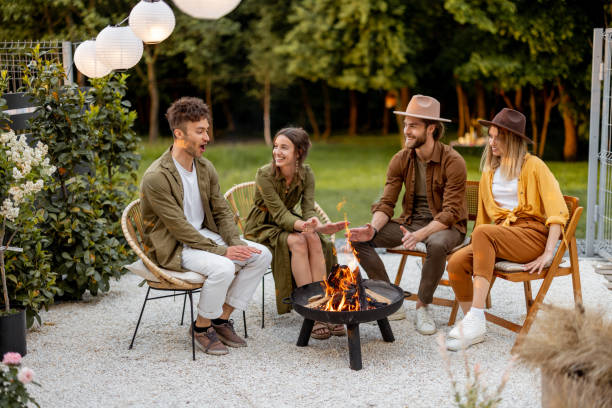 friends sitting by a fireplace at backyard - friendly fire imagens e fotografias de stock