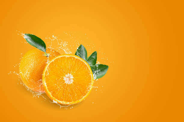 istock Water splashing on Orange juice freshly squeezed on an orange background. 1323609858