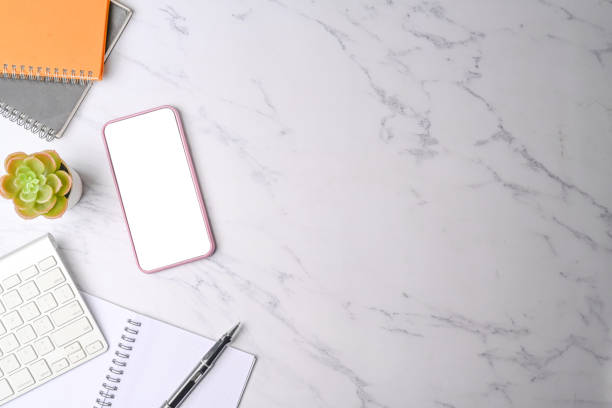 istock Smart phone, notebook and keyboard on marble background 1323621525