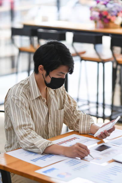 istock Businessman wearing protective mask analyzing financial data at office. 1323621594