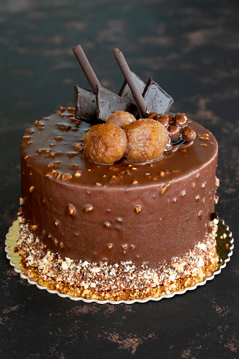 Chestnut and chocolate birthday cake on dark background
