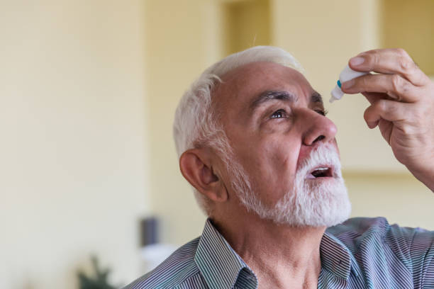 un hombre mayor está usando gotas para los ojos para una mejor visión. - pain human eye senior adult men fotografías e imágenes de stock