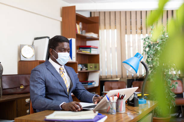 istock Businessman in protective mask focused on working with laptop 1323626943