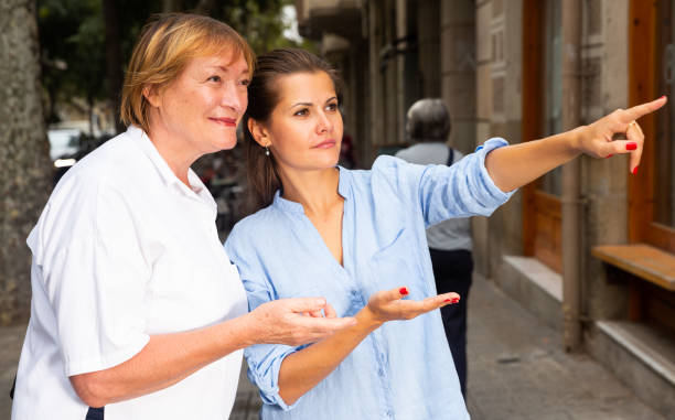 istock Young woman pointing way to middle aged female 1323627100