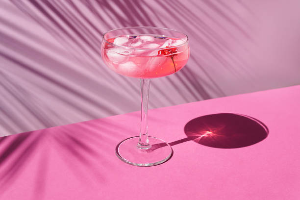 champagne rosa con ghiaccio sul tavolo con ombre solari. concetto tropicale. - martini glass immagine foto e immagini stock