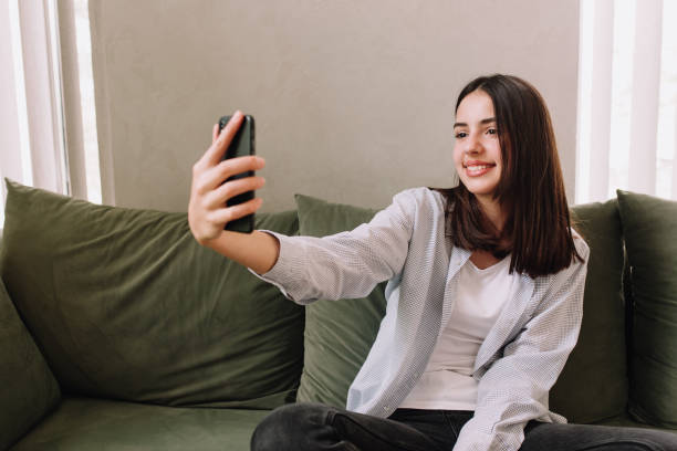 ragazza adolescente piuttosto sorridente che posa un sorriso e si fa un selfie con lo smartphone - adolescence teenagers only teenager making a face foto e immagini stock