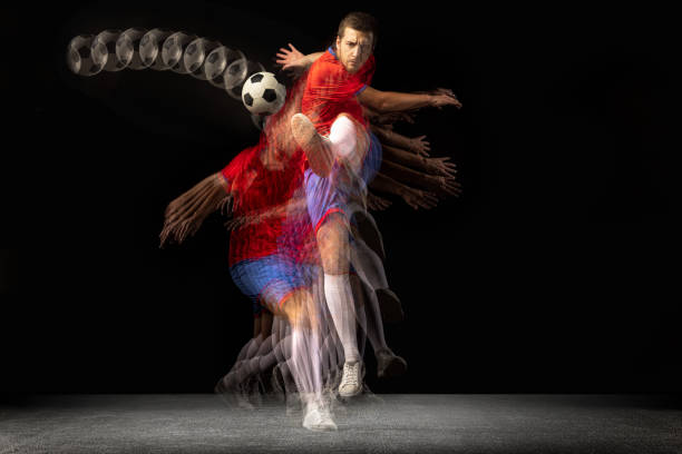 non stop bewegen. junger kaukasischer fußballer, der in bewegung in gemischtem licht auf dunklem hintergrund spielt. - stroboscopic image stock-fotos und bilder