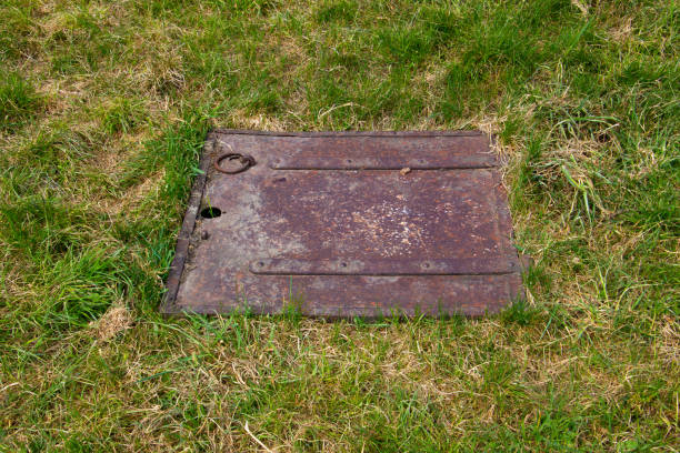 istock Close up of a old rusty metal square hatch in a grass field 1323634045