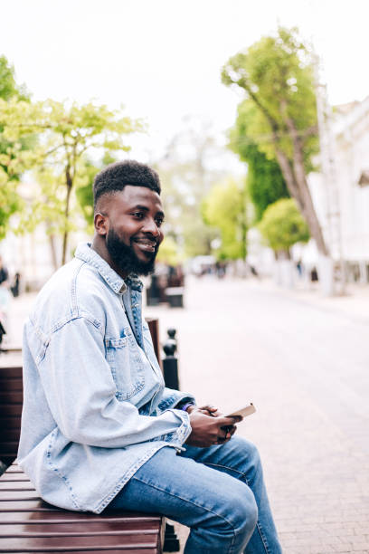 young handsome black businessman using phone outdoors. - surfing wireless vertical outdoors lifestyles imagens e fotografias de stock