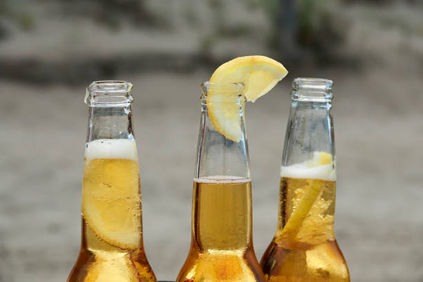 three bottles of blonde beer with lemon inside - fotografia de stock