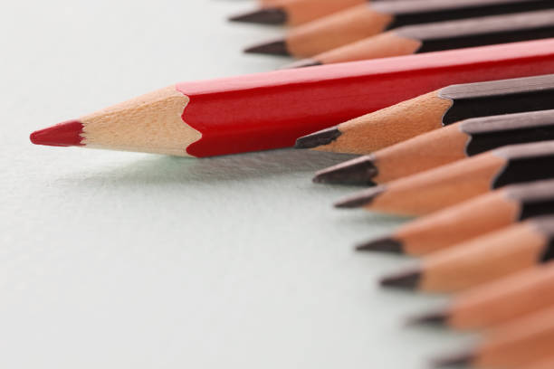 Red sharp wooden pencil lying beyond black closeup background. Leadership skills concept