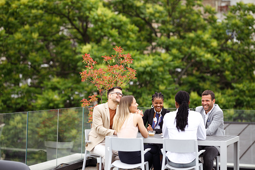 A diverse group of businesspeople is having a meeting in an outdoor restaurant.