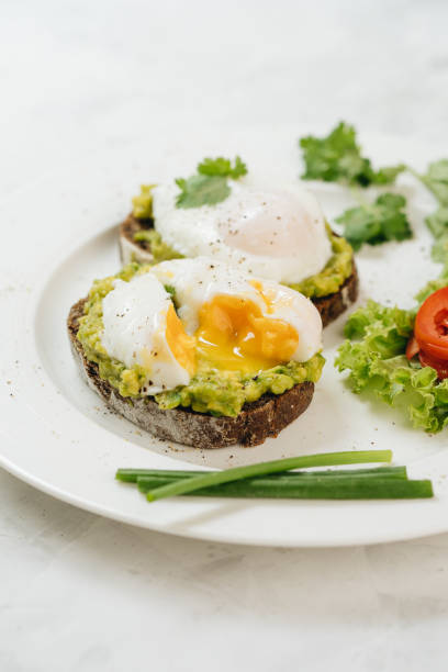 istock Poached eggs with avocado on sourdough toasts on white background 1323635329
