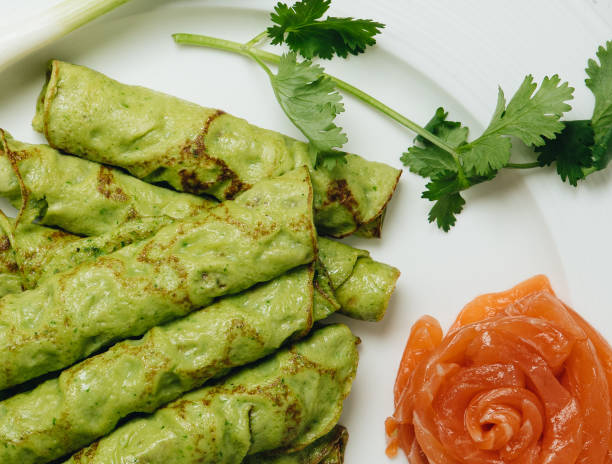 istock Spinach green Crepes with salmon on white background 1323635444