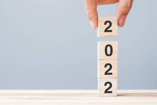 istock hand holding wooden cube block with 2022 text on table background. Resolution, plan, review, goal, start and New Year holiday concepts 1323636398