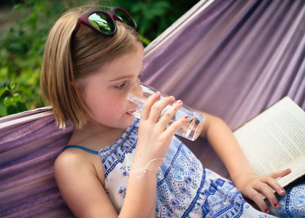 a little girl greedily drinking water from a bottle in hot weather in summer