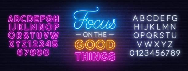 Focus on the Good Things neon lettering on brick wall background. Focus on the Good Things neon lettering on brick wall background. Inspirational glowing sign. Neon white and pink alphabet. neon coloured stock illustrations