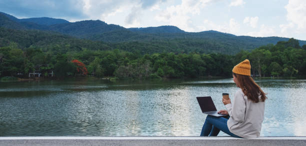 eine junge frau, die auf dem laptop-computer unterwegs ist und arbeitet - nomade stock-fotos und bilder