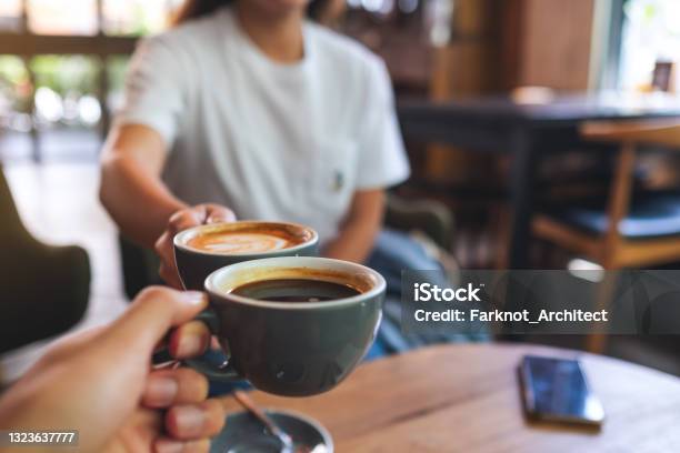 A Man And A Woman Clinking Coffee Mugs In Cafe Stock Photo - Download Image Now - Coffee - Drink, Cafe, Friendship