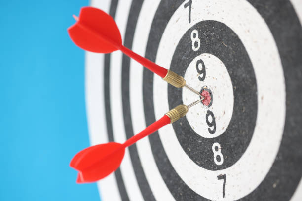 istock Two red darts hitting dart target closeup on blue background 1323637947
