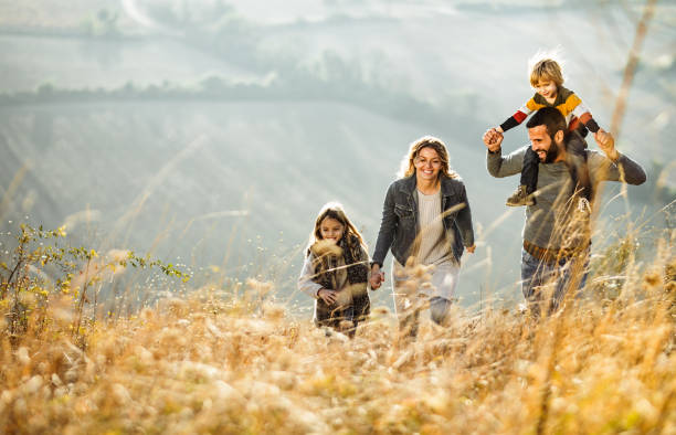 istock Carefree parents having fun while running with their kids on a field. 1323637957