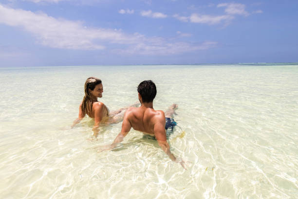 istock Happy couple talking while relaxing in shallow sea. 1323639093