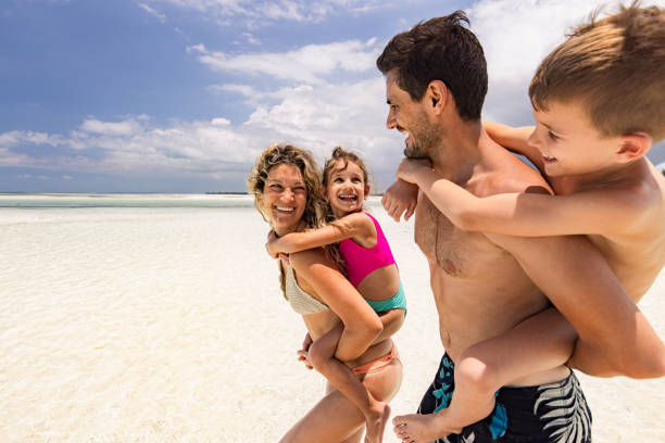 istock Happy family having fun while piggybacking on the beach. 1323639801