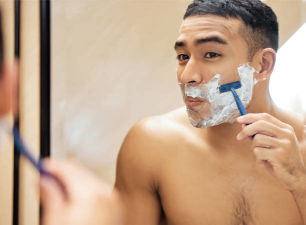 istock Shot of a young man looking in the mirror while shaving his beard 1323641303