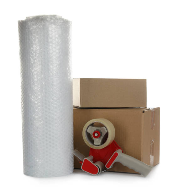 bubble pack roll, cardboard boxes and tape dispenser on white background