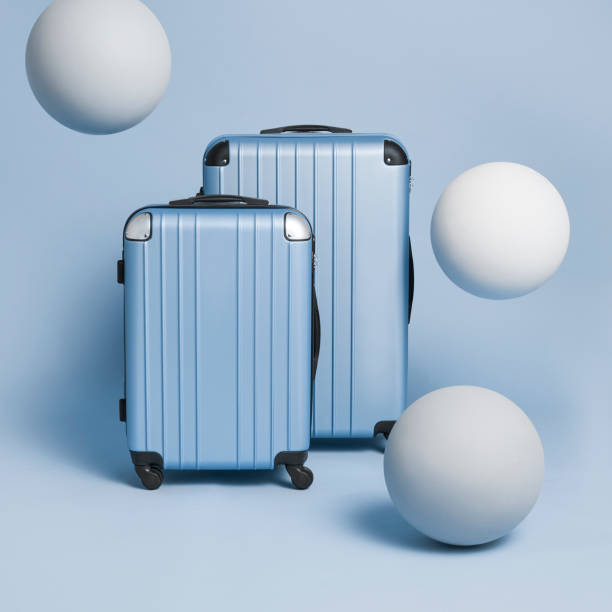 istock 2 blue suitcases on a blue bagkgrounds with big white balls flying around 1323643352