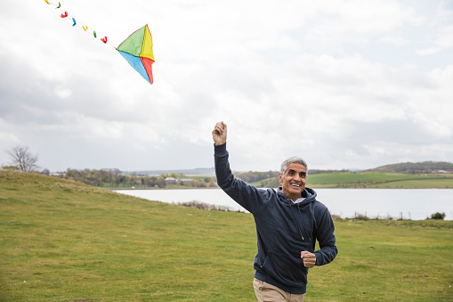 Man flying a kite in a field while running in the North East of England.