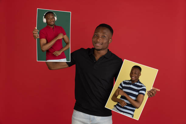 istock Young african man holding his portraits isolated over red studio background with copyspace for ad. 1323644792