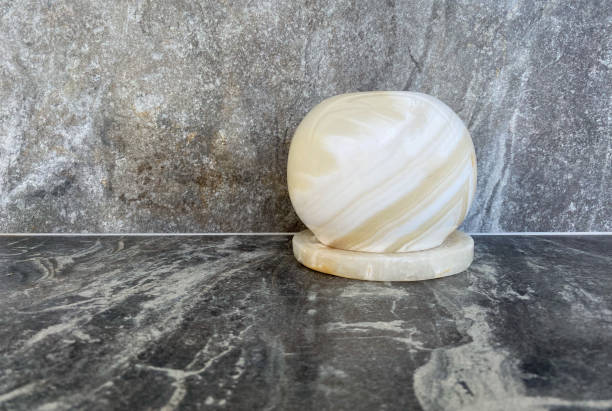 A close-up onyx candle holder stands on a grey marble table