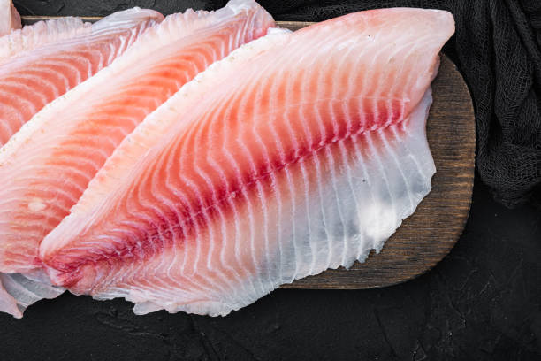 istock Raw white fish fillet, on black background, top view 1323647497