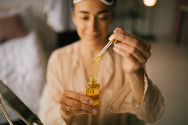 Portrait of beautiful young woman holding face oil. Beauty cosmetic concept. Portrait of beautiful young woman holding natural face oil. Beauty cosmetic concept. face serum stock pictures, royalty-free photos & images