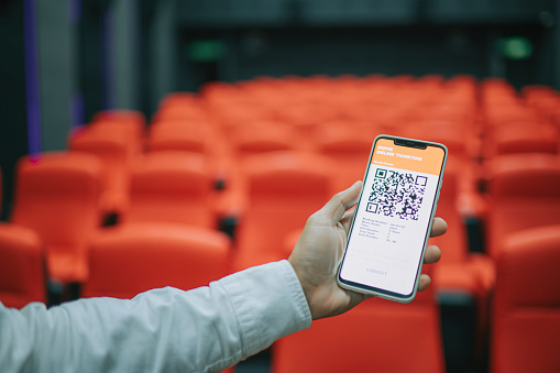 Asian Chinese Man usando la aplicación móvil Cinema Movie e-ticketing reserva buscando asiento dentro de la sala de cine photo